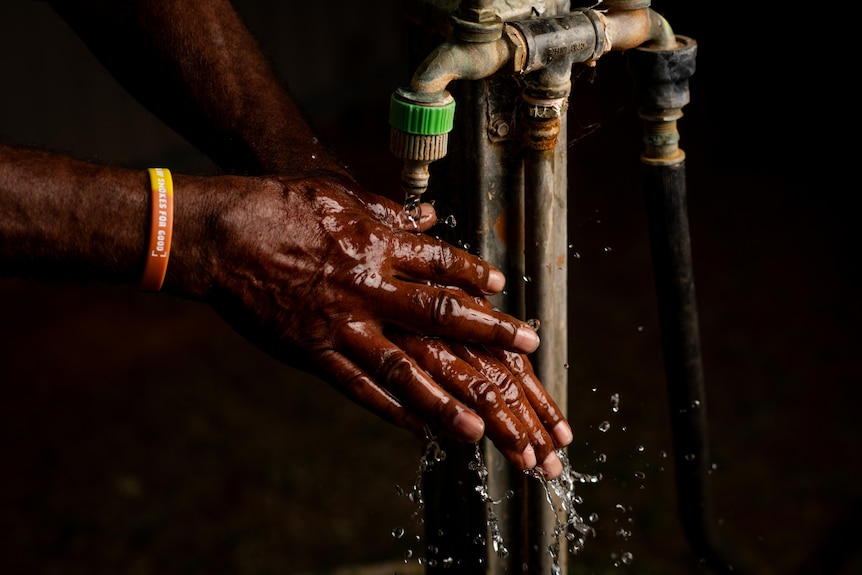A close up shot of a man's hands washing under a tap