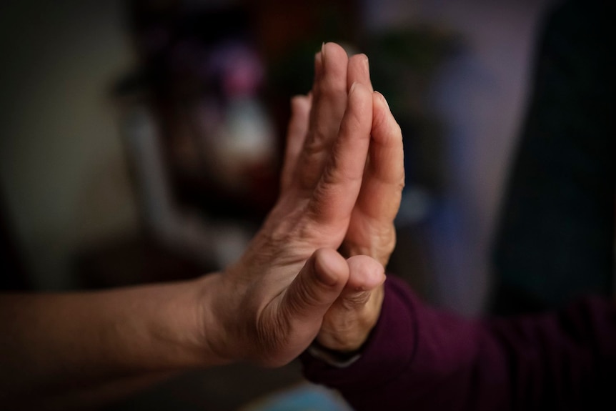 Two hands pressed together, with a blurred background.