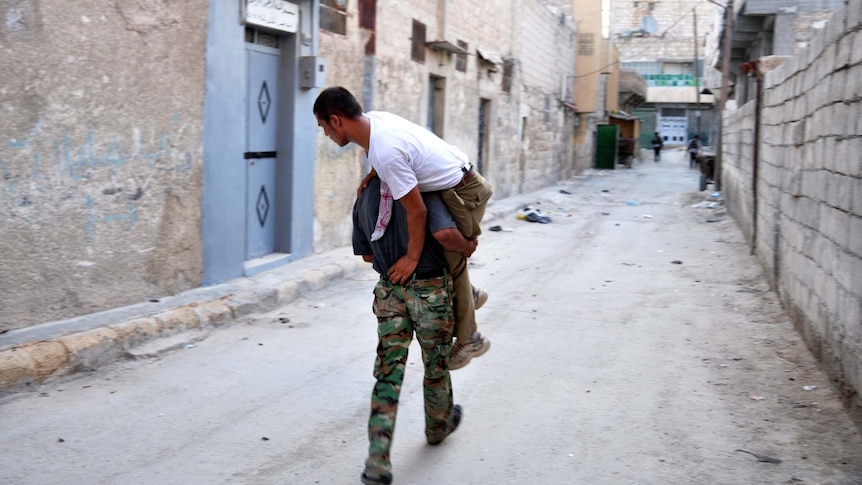 A Syrian rebel carries a comrade
