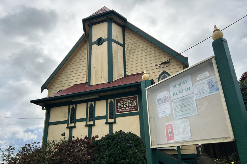 A cream and green painted church with a community noticeboard out the front