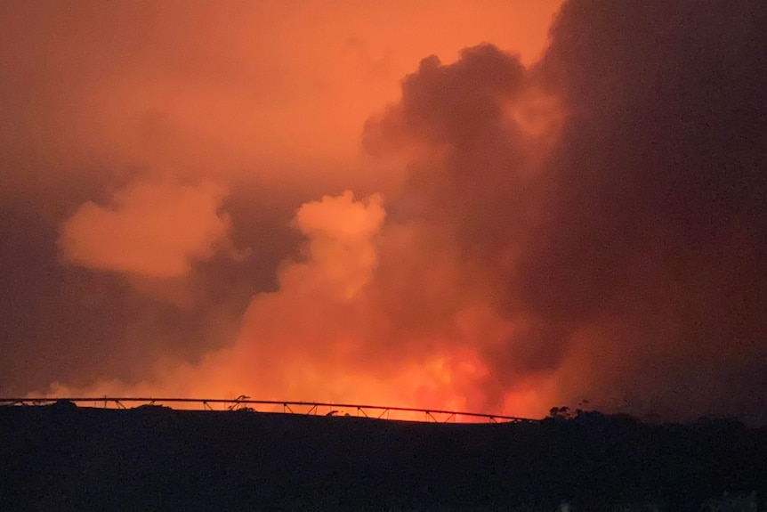 Smoke in an orange sky at night