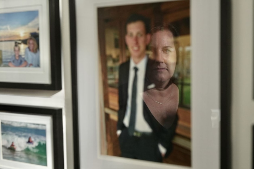 A woman's face reflected in a portrait of her son.