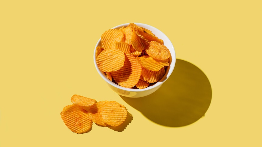 A bowl of crisps on a yellow background