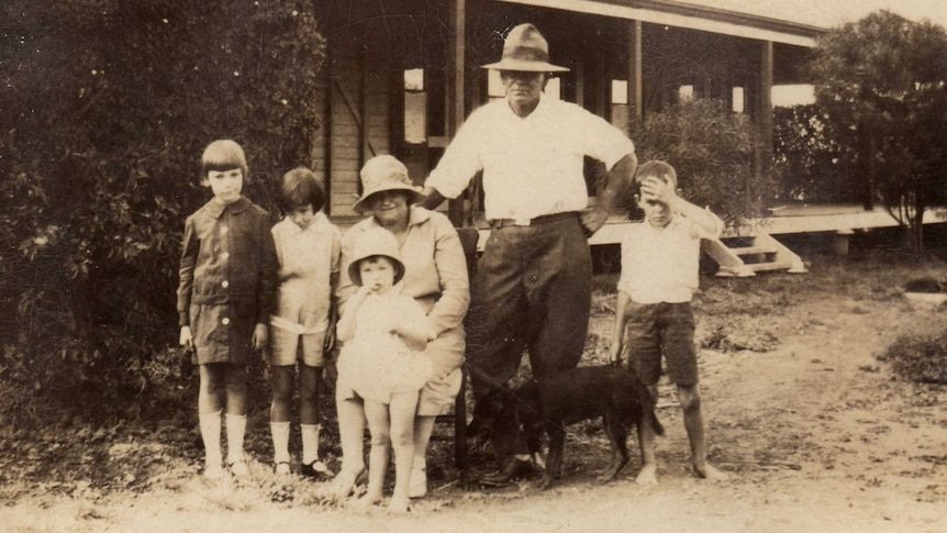A sepia photograph of the Whitehead story. A well dressed couple in hate, surrounded by four children.