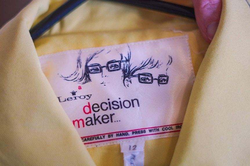 A white label inside a yellow jacket with two drawn faces and the words 'Leroy. Decision Maker'.
