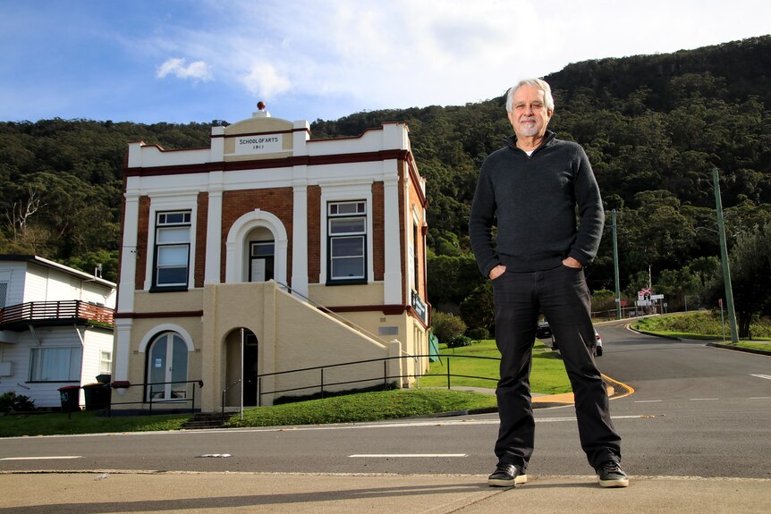 David Roach stands in a black jumper and jeans across the road from the Clifton School of Arts building.