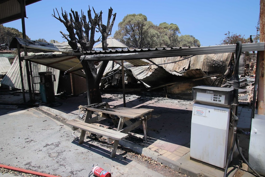 A burnt out petrol station with cyclone fencing around it.