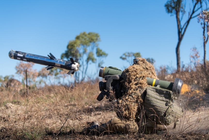 An Australian soldier in camouflage fires a javelin missile from his shoulder in a bushland training area near Townsville.