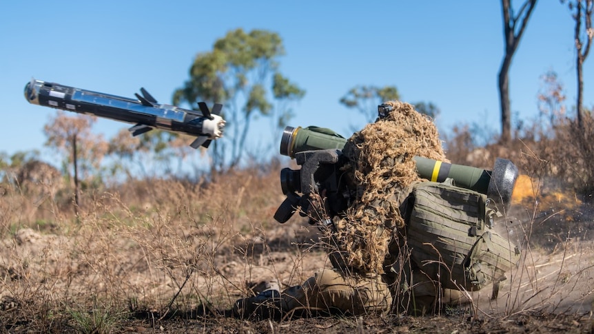 An Australian soldier in camouflage fires a javelin missile from his shoulder in a bushland training area near Townsville.