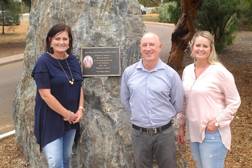 The daughters of former Whyalla Mayor Jim Pollock standing with Eddie Hughes, in front of a plaque commemorating Mr Pollock.
