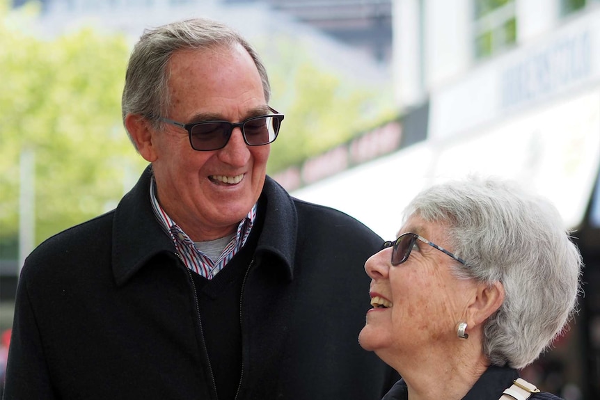 An older couple smile at each other in a city