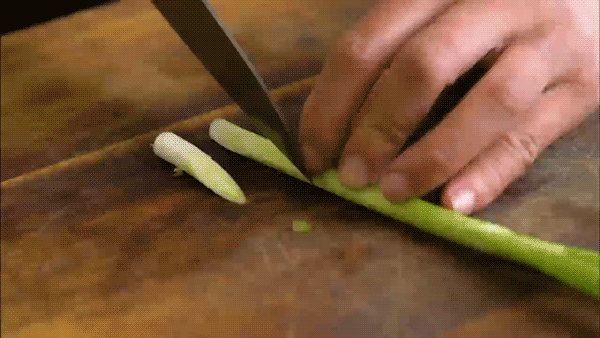 Thi Le demonstrates the 'drawback method' while cutting a spring onion.