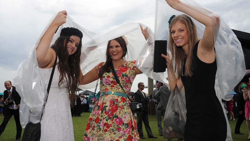 Race-goers take shelter from the rain