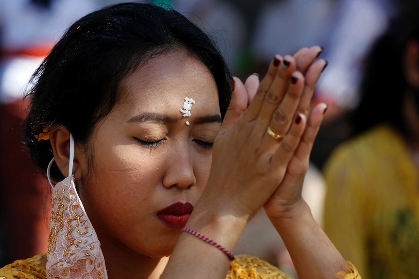 A woman closes her eyes and places her palms together as she prays.