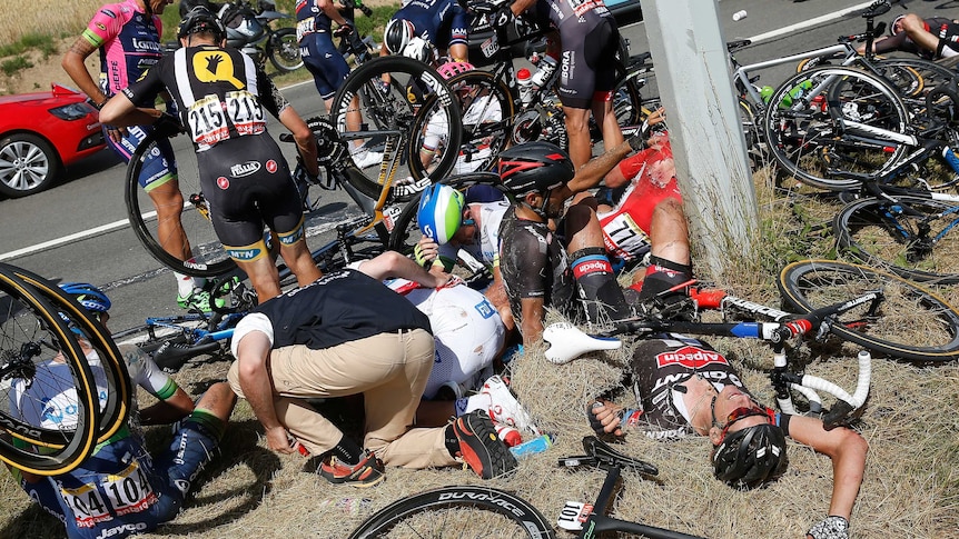 Simon Gerrans (C) and other riders lie on ground after crash on stage three of Tour de France.