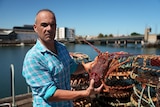 A man holds up a lobster
