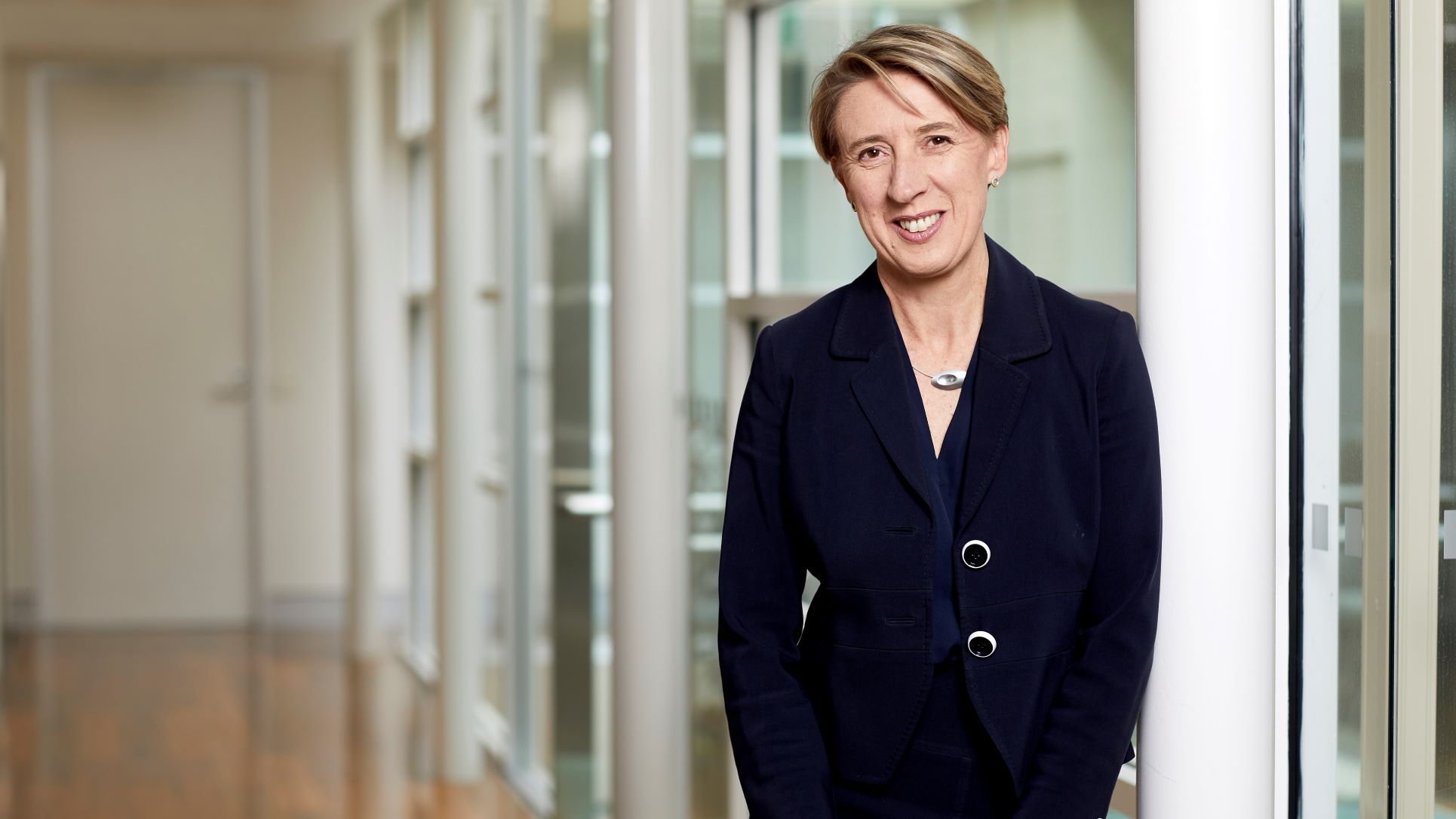 A woman wearing a black shirt standing and smiling to the camera.