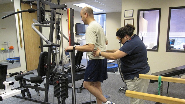 A man goes through a physical therapy session and is assisted through a leg exercise by his physio