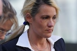 A woman outside court with a black jacked and white shirt, surrounded by three other people.