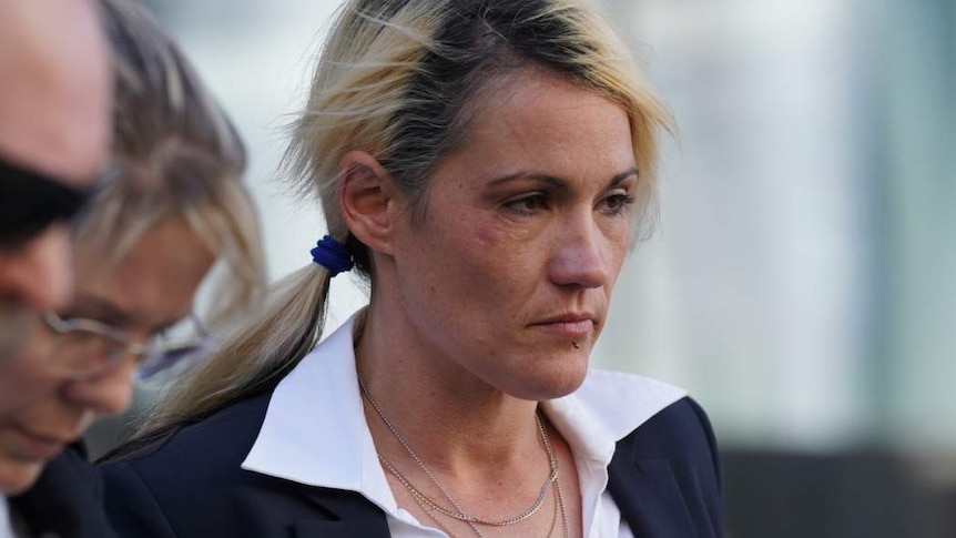 A woman outside court with a black jacked and white shirt, surrounded by three other people.