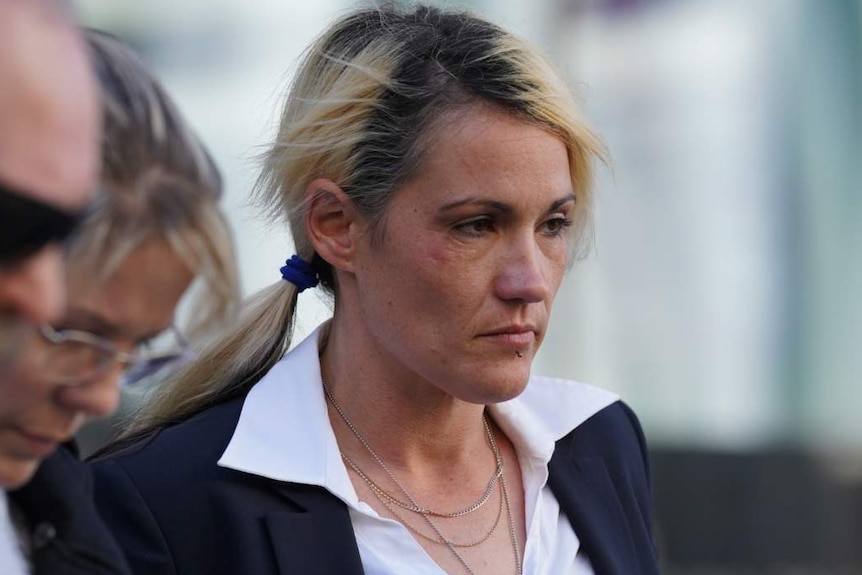 A woman outside court with a black jacked and white shirt, surrounded by three other people.