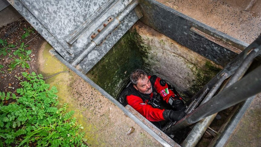 A diver lowers himself into Tank Cave.