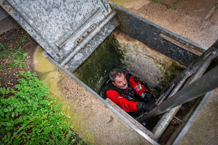 A diver lowers himself into Tank Cave.