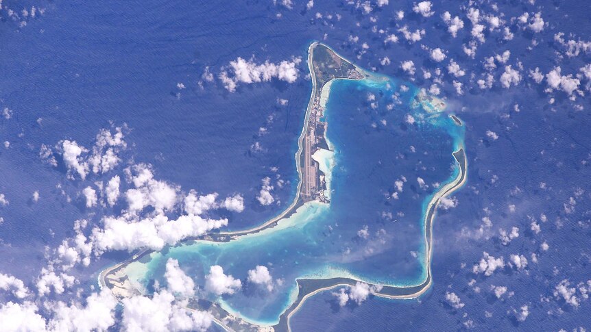 An atoll with clouds, as seen from high above.
