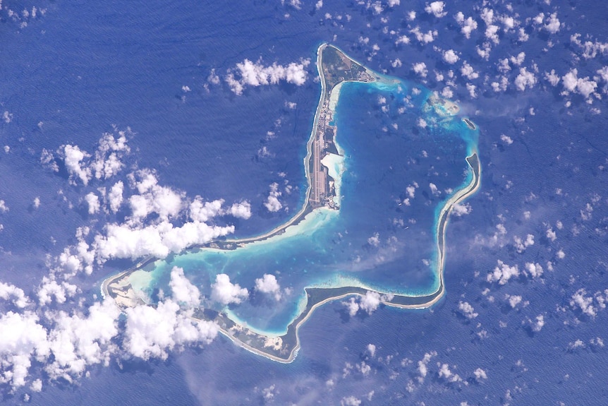An atoll with clouds, as seen from high above.