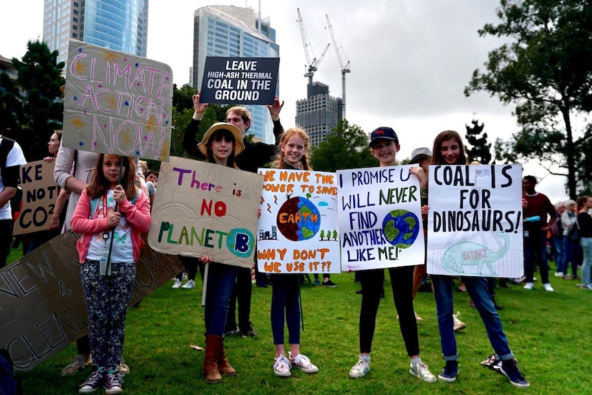 A group of school-aged children hold signs calling for action to protect the climate.