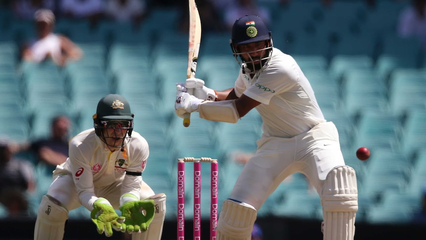 India batsman Cheteshwar Pujara is in his back swing for a powerful pull shot as Australia wicketkeeper Tim Paine watches on.