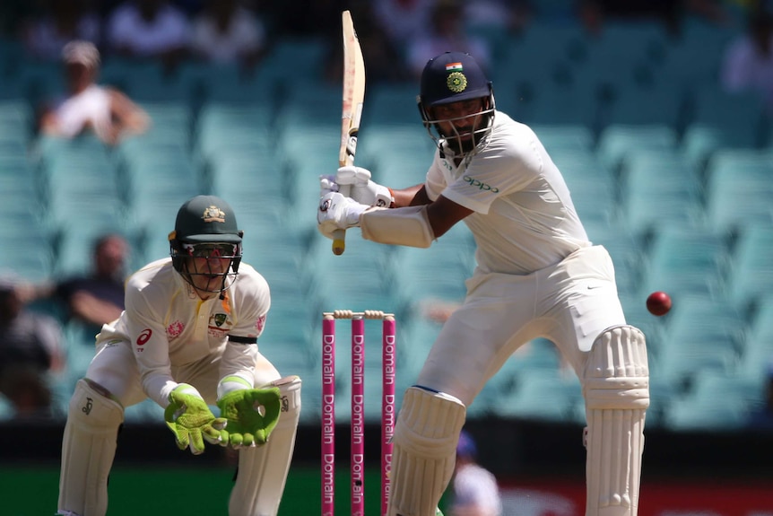 India batsman Cheteshwar Pujara is in his back swing for a powerful pull shot as Australia wicketkeeper Tim Paine watches on.