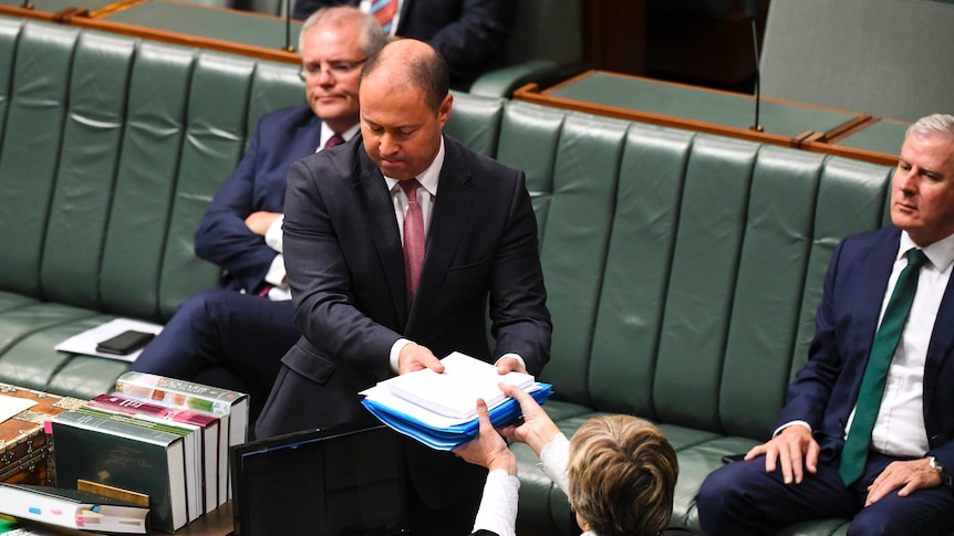 Josh Frydenberg hands over bills to the clerk in the House of Representatives