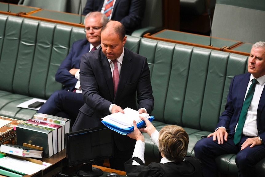 Josh Frydenberg hands over bills to the clerk in the House of Representatives