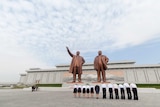 Workers bow before statues of Kim Il-sung and Kim Jong-il at a monument in Pyongyang.