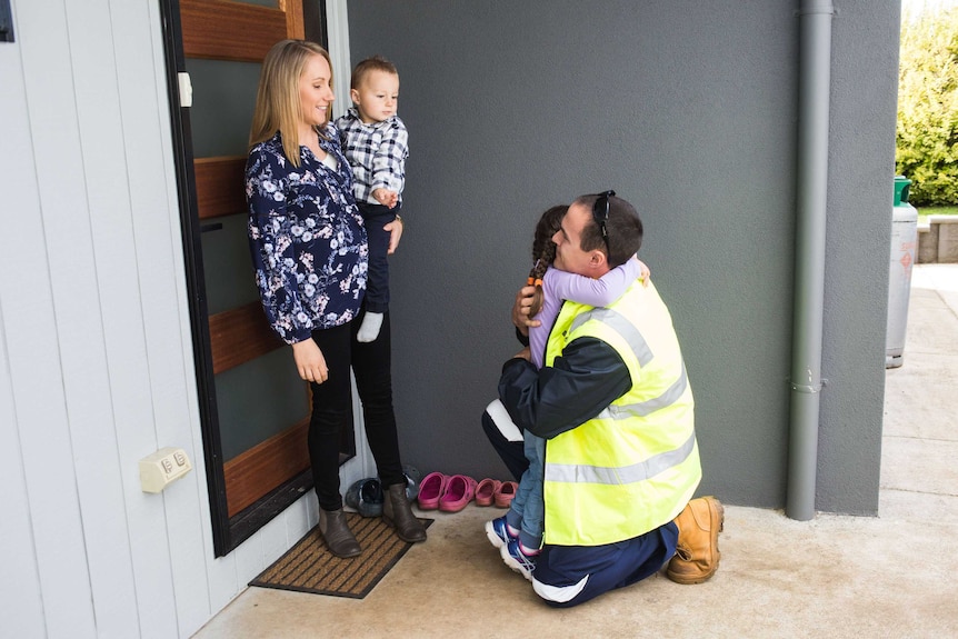 A man farewells a woman and children at a a doorway.