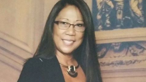 Marilou Danley smiles on a staircase wearing formal wear attire