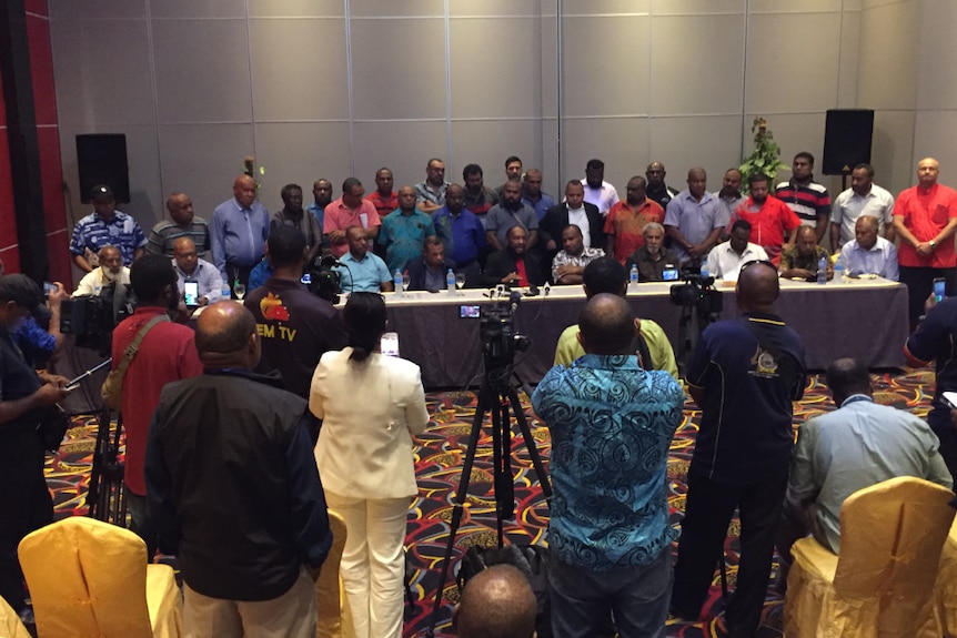 A group of PNG politicians standing in a group before a media pack