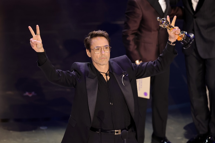 Robery Downey Jnr gestures to the audience from onstage at the 2024 Oscars.
