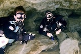 Two divers in wet suits in cave