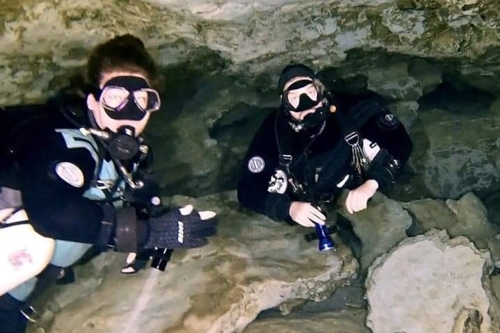 Two divers in wet suits in a cave.