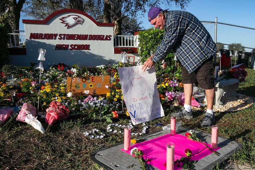 Jack Jozefs places a sign outside Marjory Stoneman Douglas High School