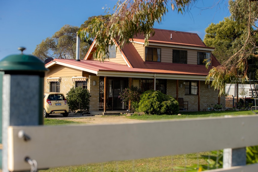 A 2 storey red roof, cream brick home.