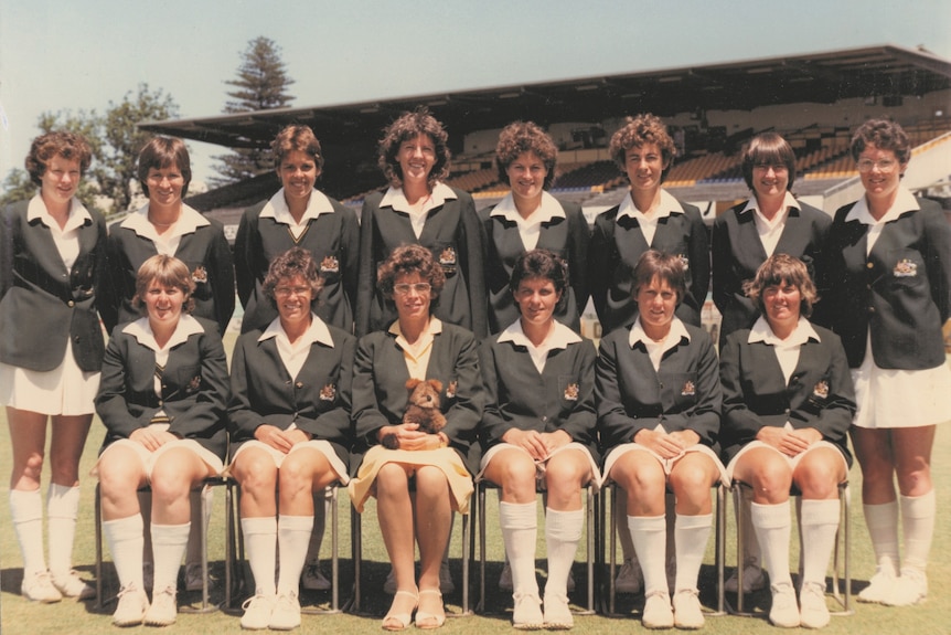 Photo of the Australian women's cricket team with players wearing blazers, with the front row seated and the back row standing.
