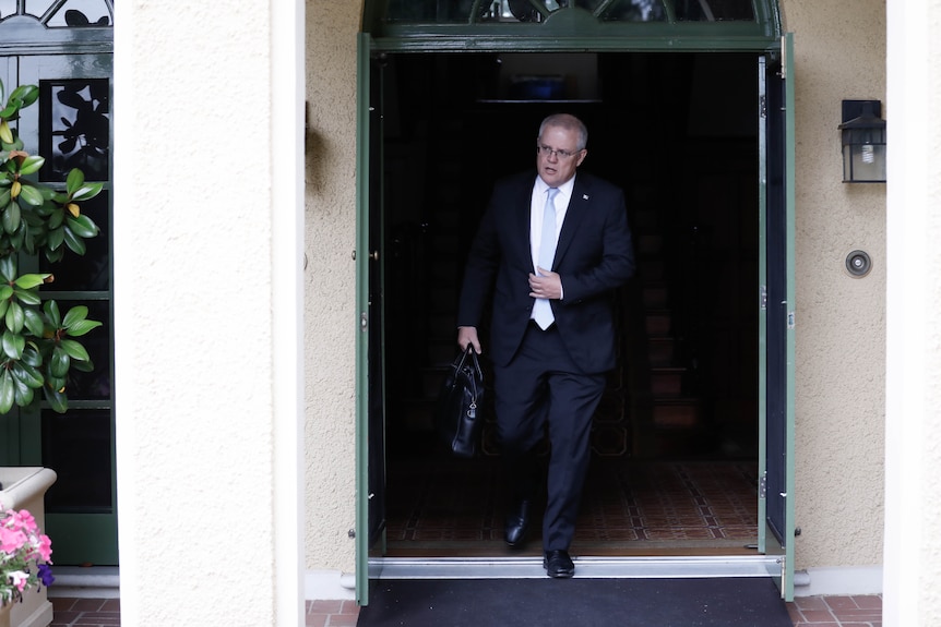 A man in a suit walks out of a doorway