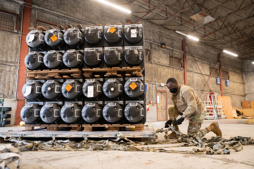 a US airman prepares weapons to be sent to Ukrain on pallets at Dover Air Force Base in Delaware, US