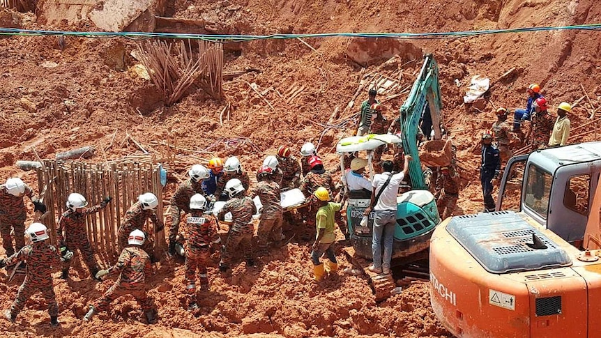 Many rescue workers are seen carrying a stretcher from the debris of the landslide.
