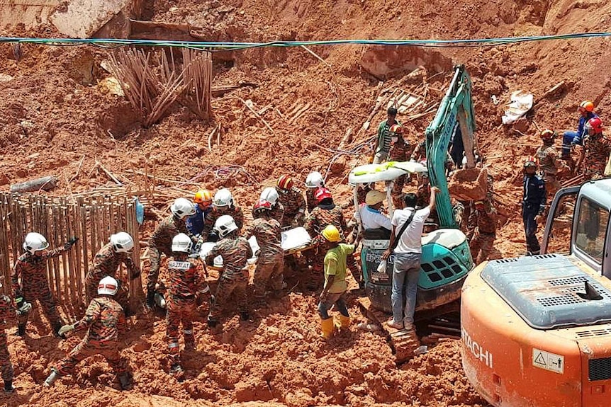 Many rescue workers are seen carrying a stretcher from the debris of the landslide.