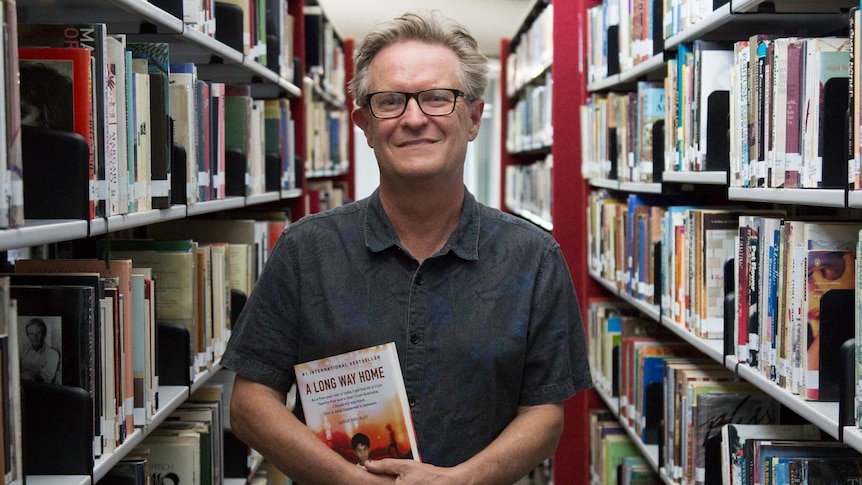 Larry Buttrose poses with his book