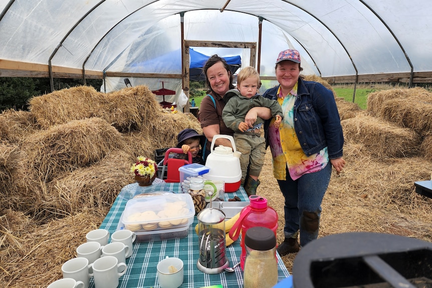 A  young lady with her mum and son at a picnic table on a farm.